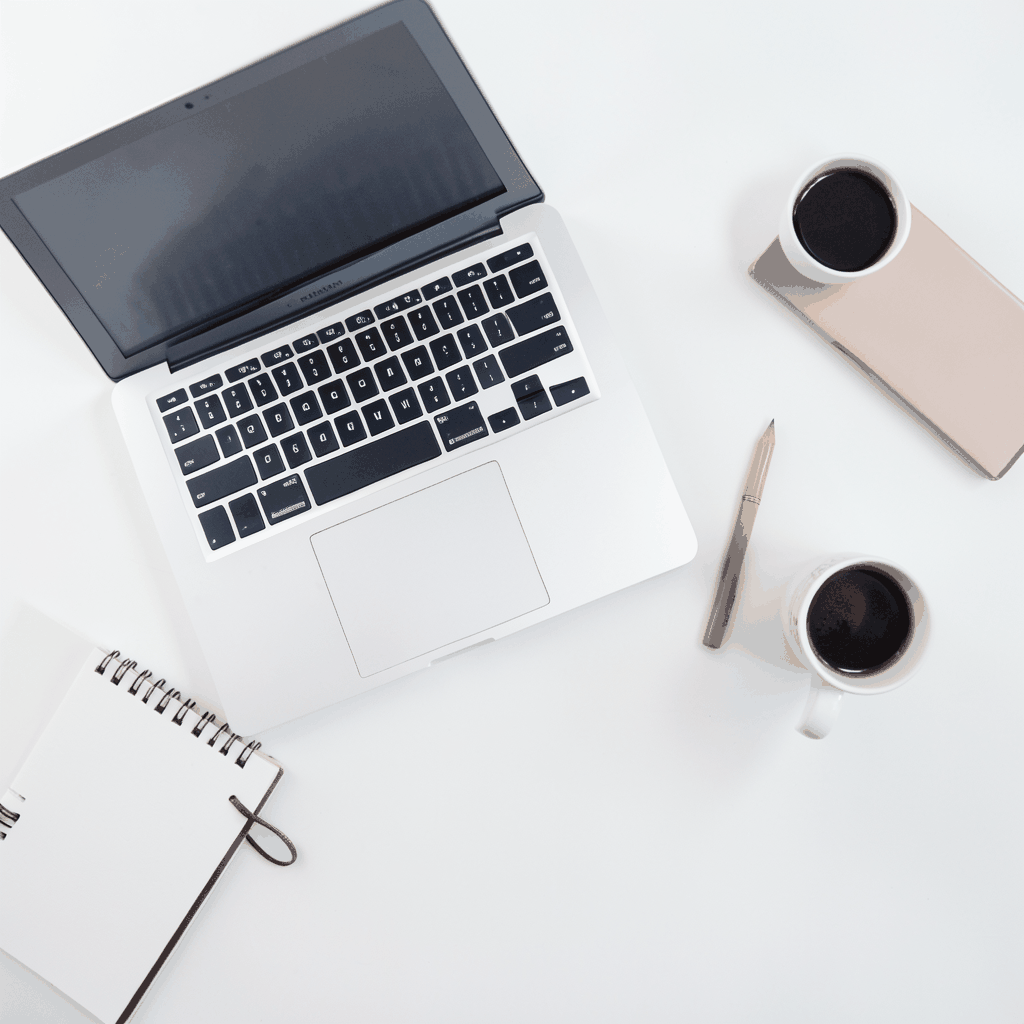 Flat-lay overhead photograph of a clean white desk surface with a laptop, notebook, and coffee cup, predominantly white